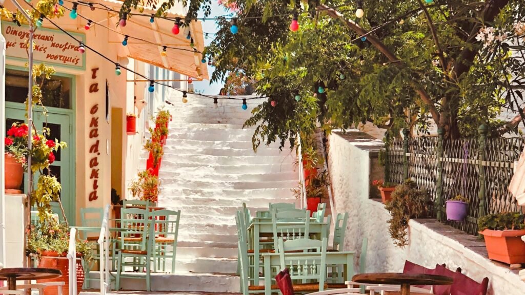 Ξύλινα τραπέζια και καρέκλες σε αυλή καταλύματος με δέντρα
